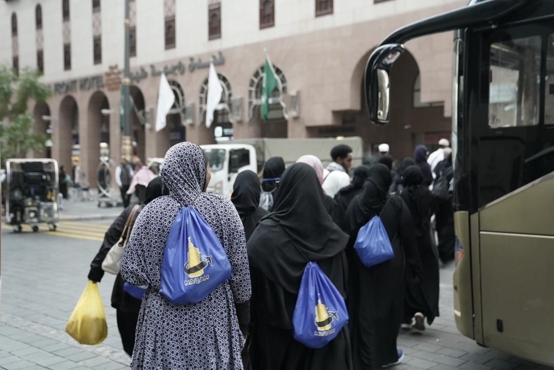 Sisters of a past journey with their Maqam Umrah bags boarding the group coach